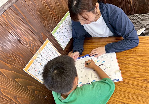 あそび王国：女性スタッフが子どもに勉強を教える様子